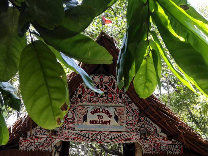 Traditional thatched roof entrance with decorative tribal painted motifs.